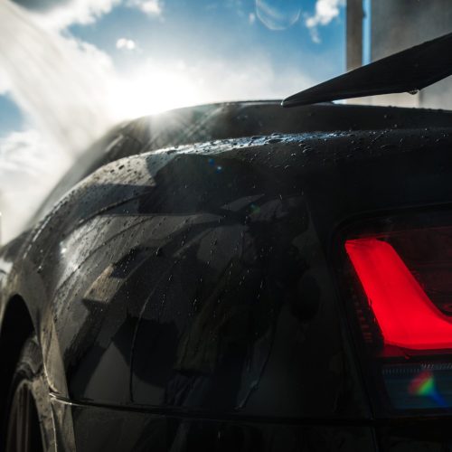 Modern Black Sports Car Inside a Car Wash. Vehicle Pressure Washing and Cleaning. Modern Black Sports Car Inside a Car Wash. Vehicle Pressure Washing and Cleaning.